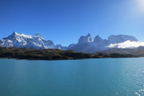 a body of water with mountains in the background with Torres del Paine National Park in the background