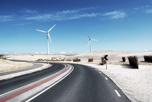 a road with wind turbines in the distance