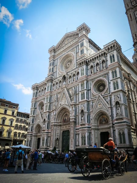 a horse carriage in front of a large building with Florence Cathedral in the background