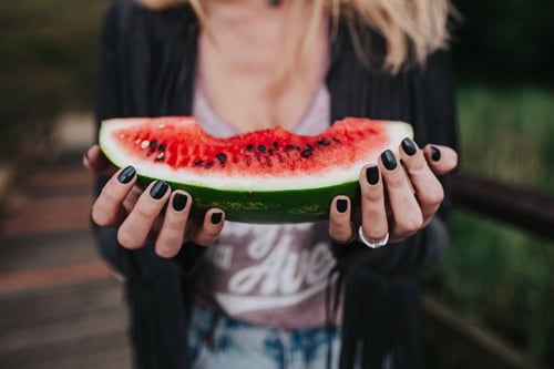 a woman holding a slice of watermelon