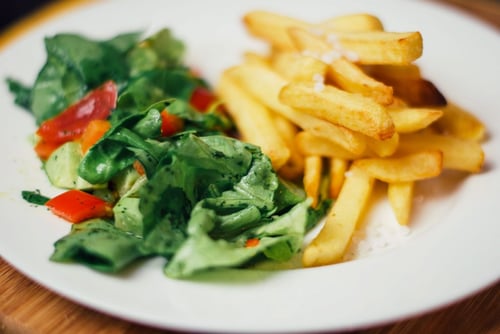 french fries with a cucumber tomato and green lettuce salad
