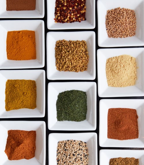 a group of white square bowls with different spices