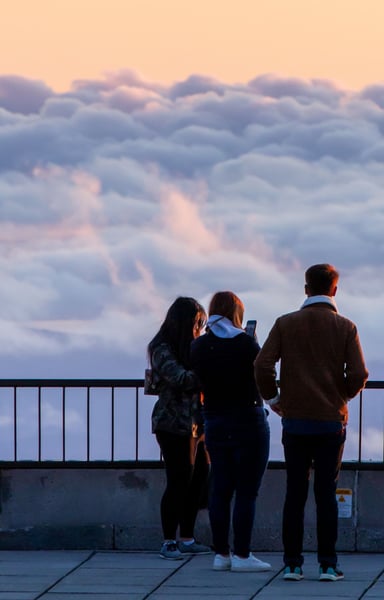 a group of people standing on a balcony overlooking clouds