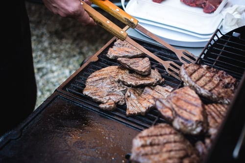 a person cooking meat on a grill
