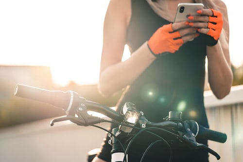 a person holding a phone while sitting on a bicycle