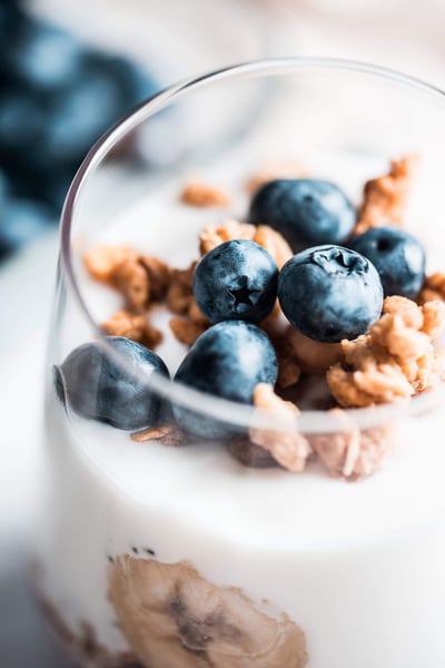 a glass of yogurt with blueberries and granola