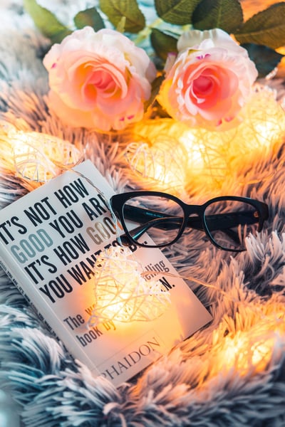a book and glasses on a blanket with flowers