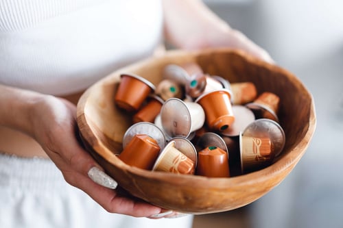 a person holding a bowl of coffee capsules