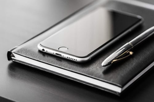 a cell phone and pen on a notebook