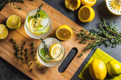a pair of glasses with ice and lemons on a wooden board