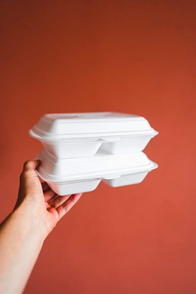 a hand holding a stack of styrofoam food containers