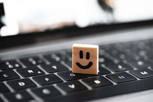 a wooden block with a smiley face on a keyboard