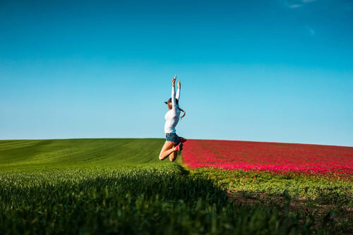 a woman jumping in the air in a field of flowers