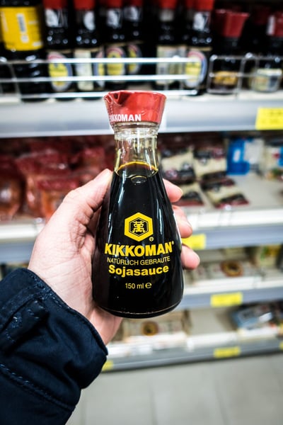 a hand holding a bottle of soy sauce