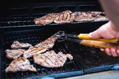a person cooking meat on a grill