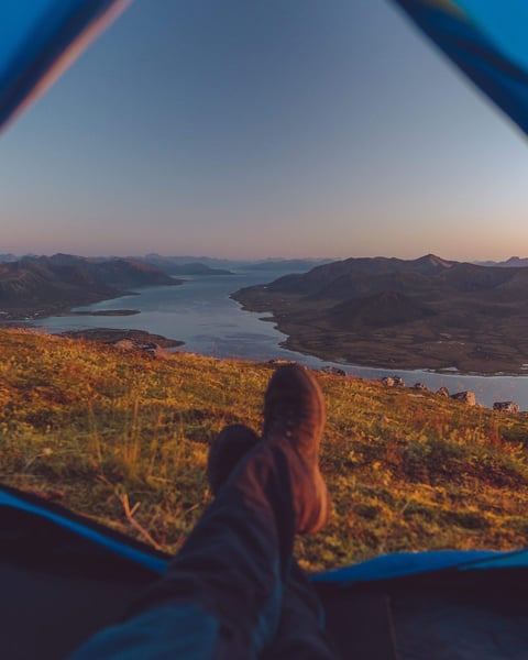 a person's feet in a tent overlooking a river