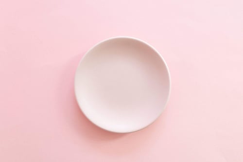 a white plate on a pink background