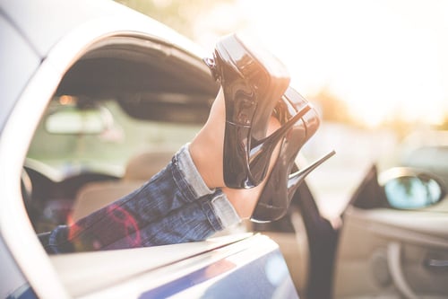 a woman's legs in a car with high heels