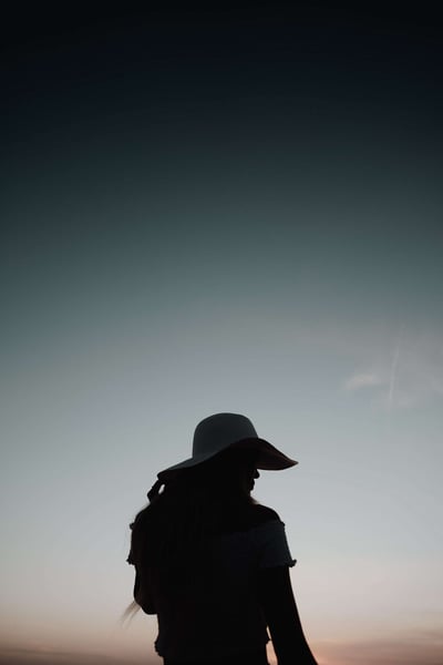a silhouette of a woman wearing a hat