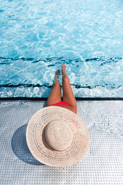 a woman sitting in a pool with a hat