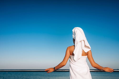 a woman wearing a towel on her head standing by a railing