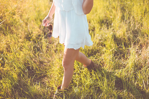 a woman in a white dress walking in a grassy area