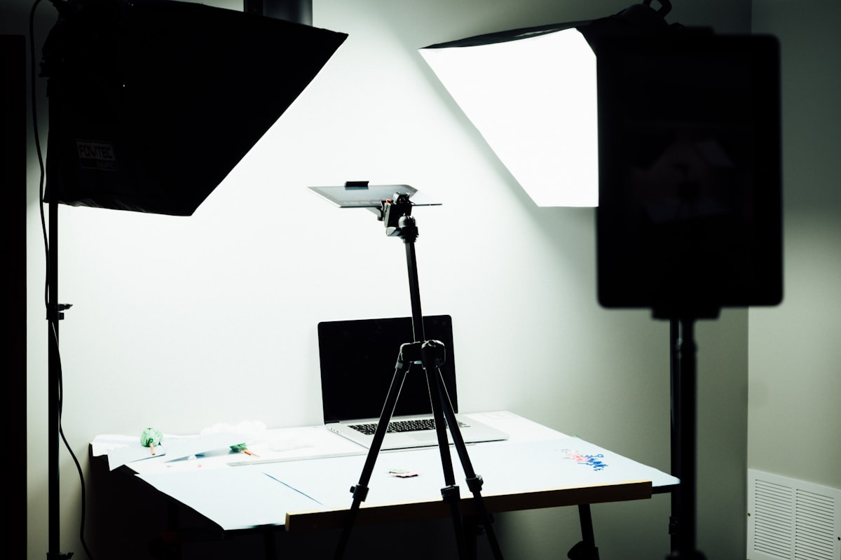 Două softbox-uri mari luminând un mic set de filmat, cu un laptop montat pe un stativ