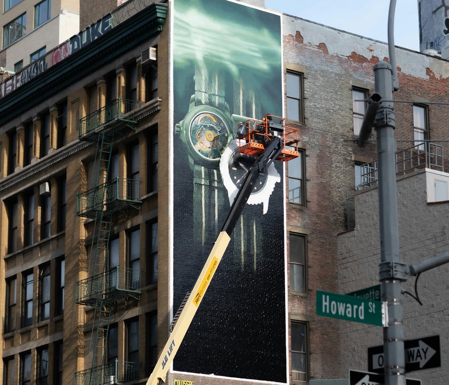 Installation in out-of-home (OOH) advertising shown by worker in boom lift pasting spectacular on building