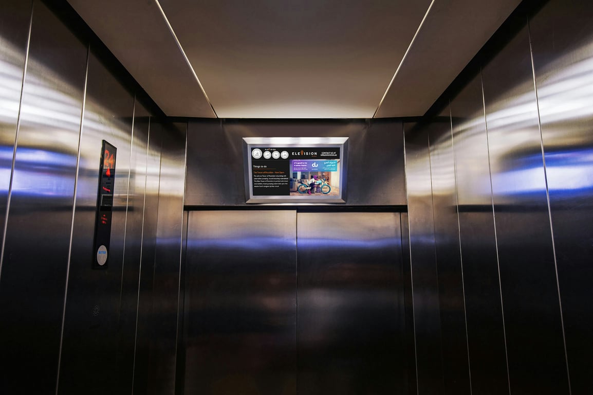 Elevator advertising in out-of-home (OOH) advertising shown by interior of elevator with sign above doors
