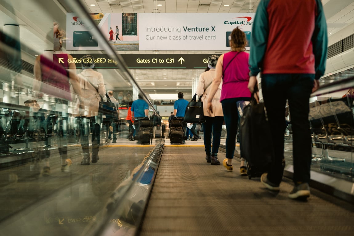 Airport advertising in out-of-home (OOH) advertising depicted by people on a horizontal escalator walking toward banner ad