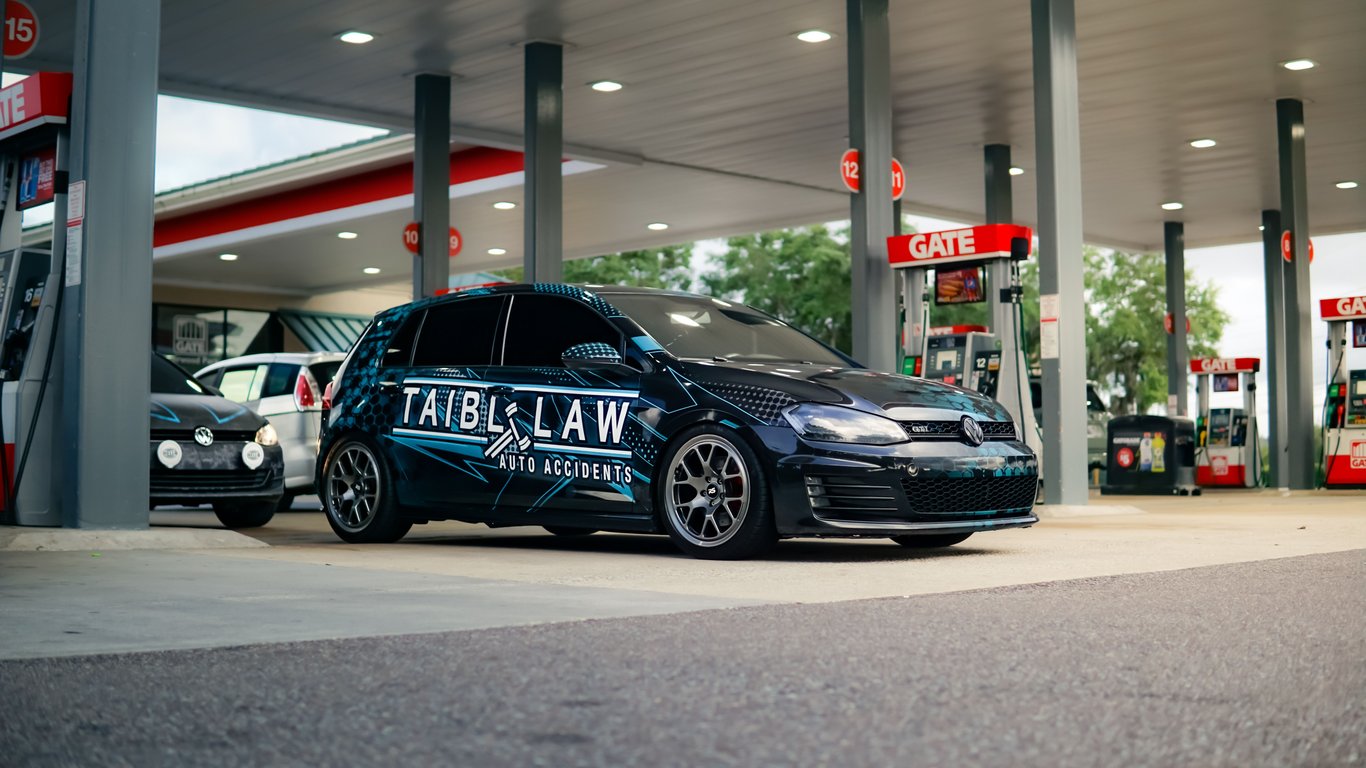 Wrapped vehicle with ad for law firm parked at gas station