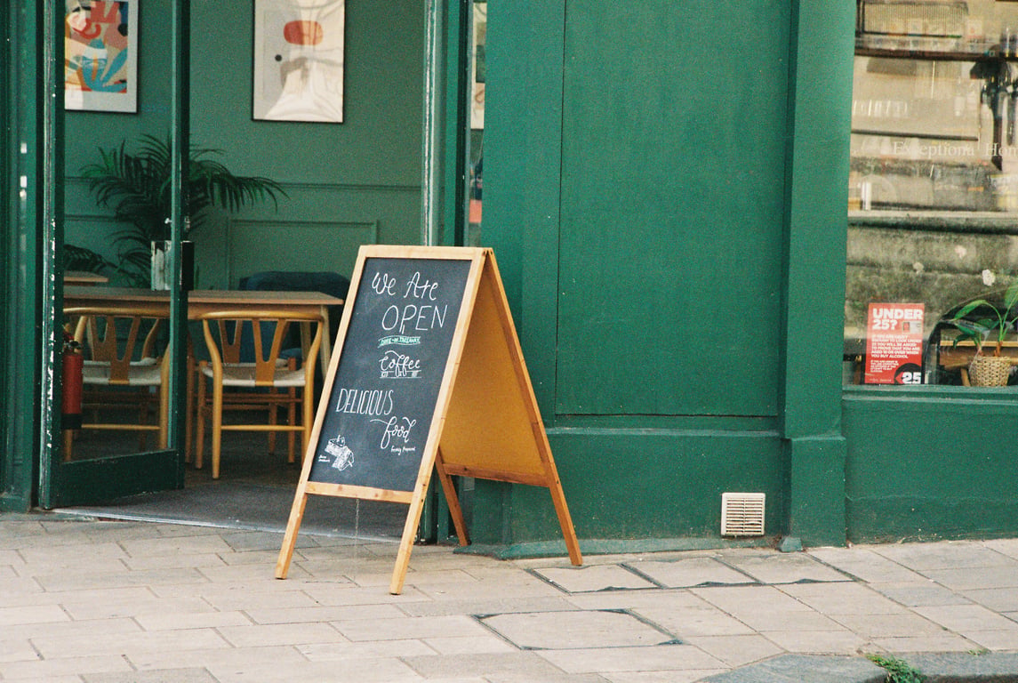 A-board in out-of-home (OOH) advertising depicted by sandwich board in front of a cafe