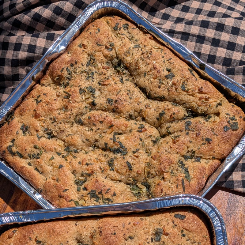 Two Italian herb focaccia bread in a pan