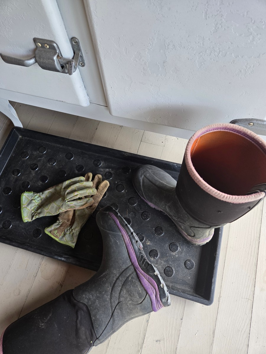 garden boots and gloves sitting on a shoe mat