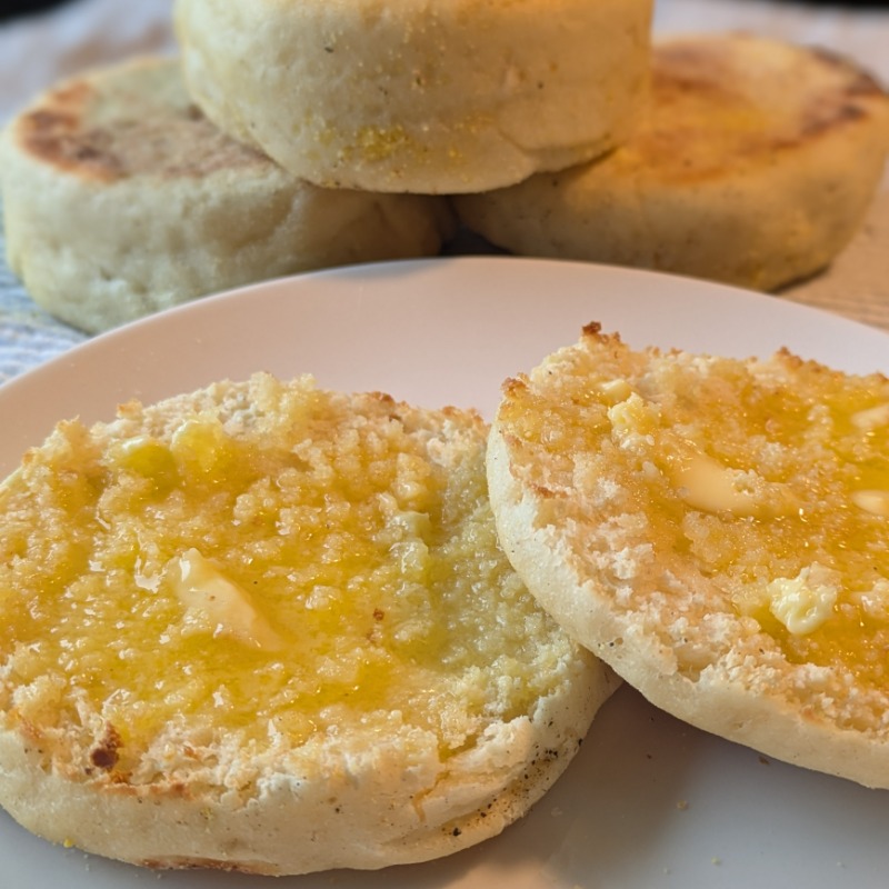English muffin fork split with melted butter and three more muffins in the background