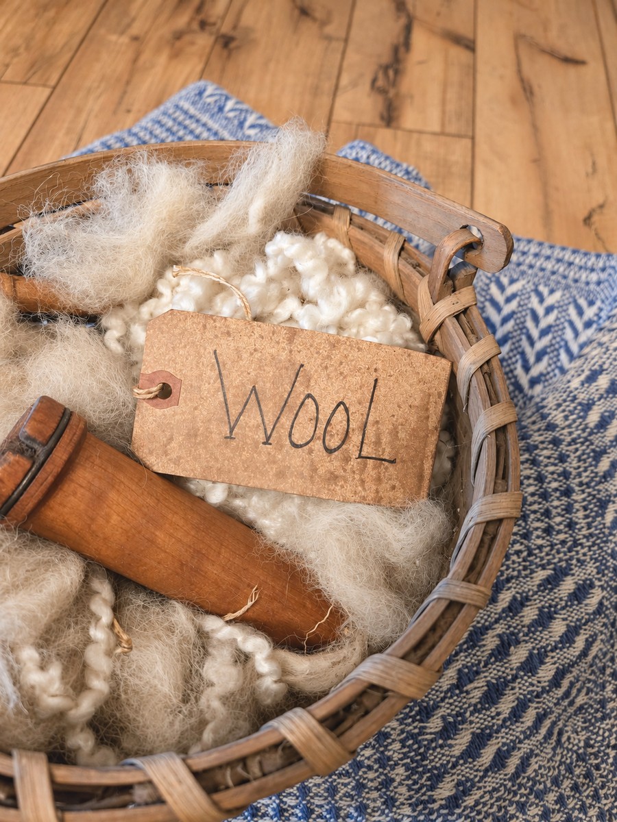 A basket of alpaca wool, old spinning wheel spools, and a tag that reads "wool".