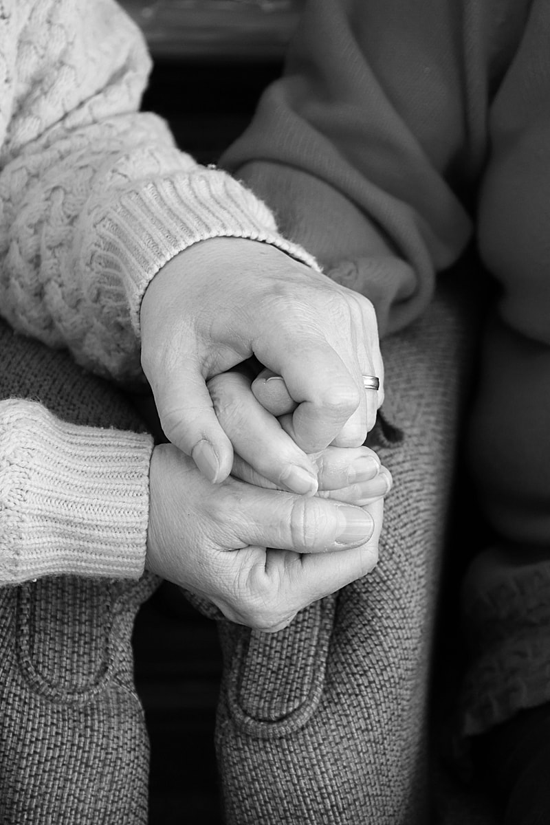 close up of a grown up daughter holding her elderly mother's hand