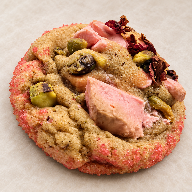 Thick gourmet cookie topped with pink chocolate, edible rose petals, honey-roasted pistachios, and pink sugar.