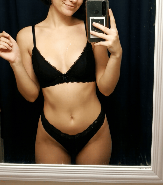 Seksikäs selfie kuva kassaneidistä. Nuori siro nainen peilin edessä, yllään mustat pitsiset alusvaatteet.