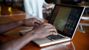 African stock video of a black African man sitting at a restaurant typing on his laptop computer e1569954406192