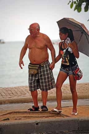 An old Western man holding hands with a young Thai lady in Pattaya