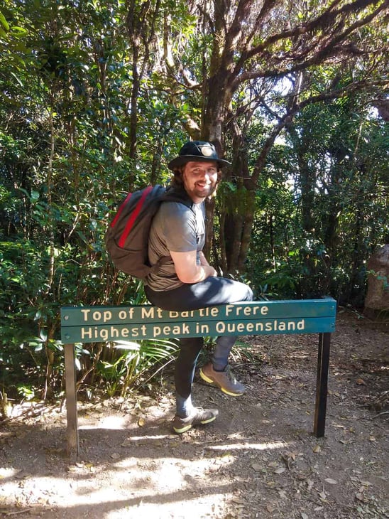 The Sailor standing at the Mount Bartle Frere summit sign, Australia // Travel Mermaid