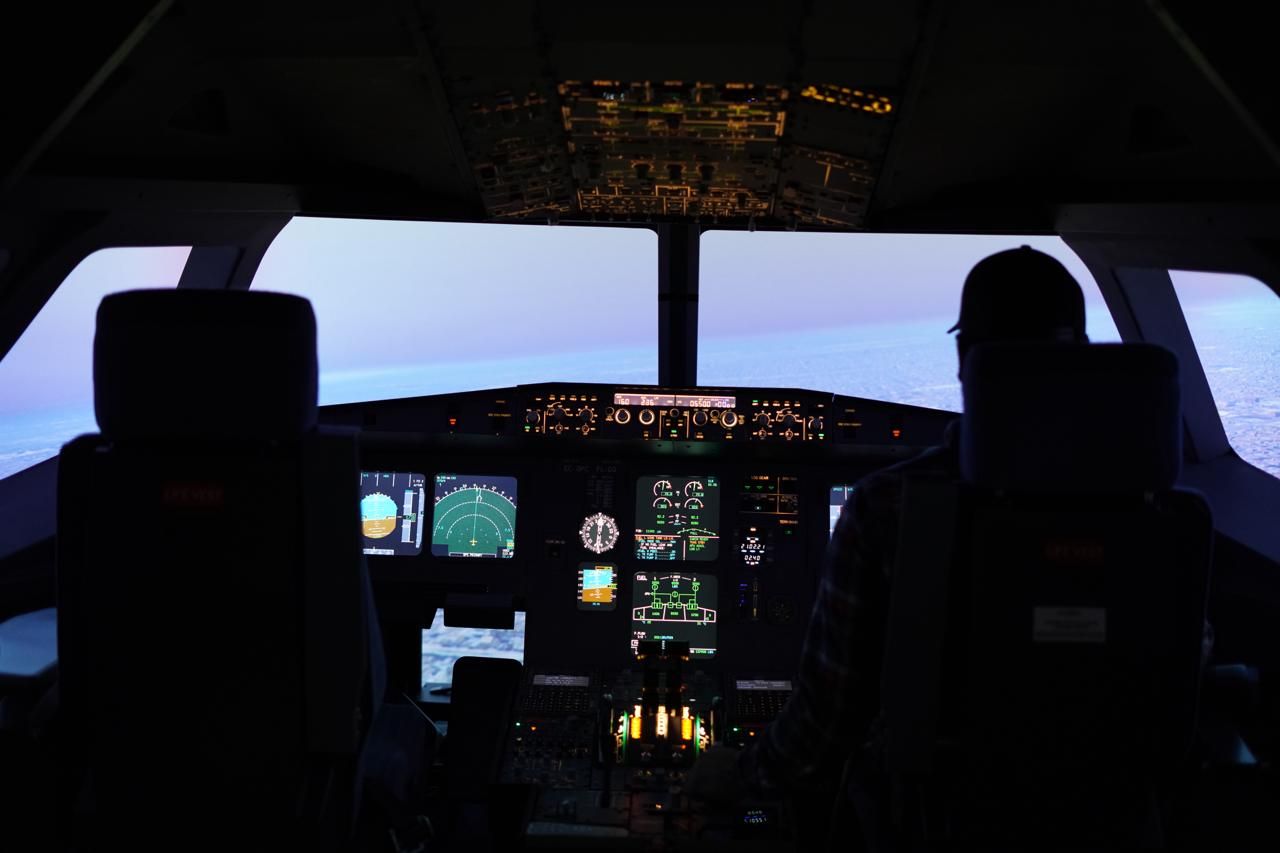 Full view of Airbus A320 flight simulator cockpit in dark lighting