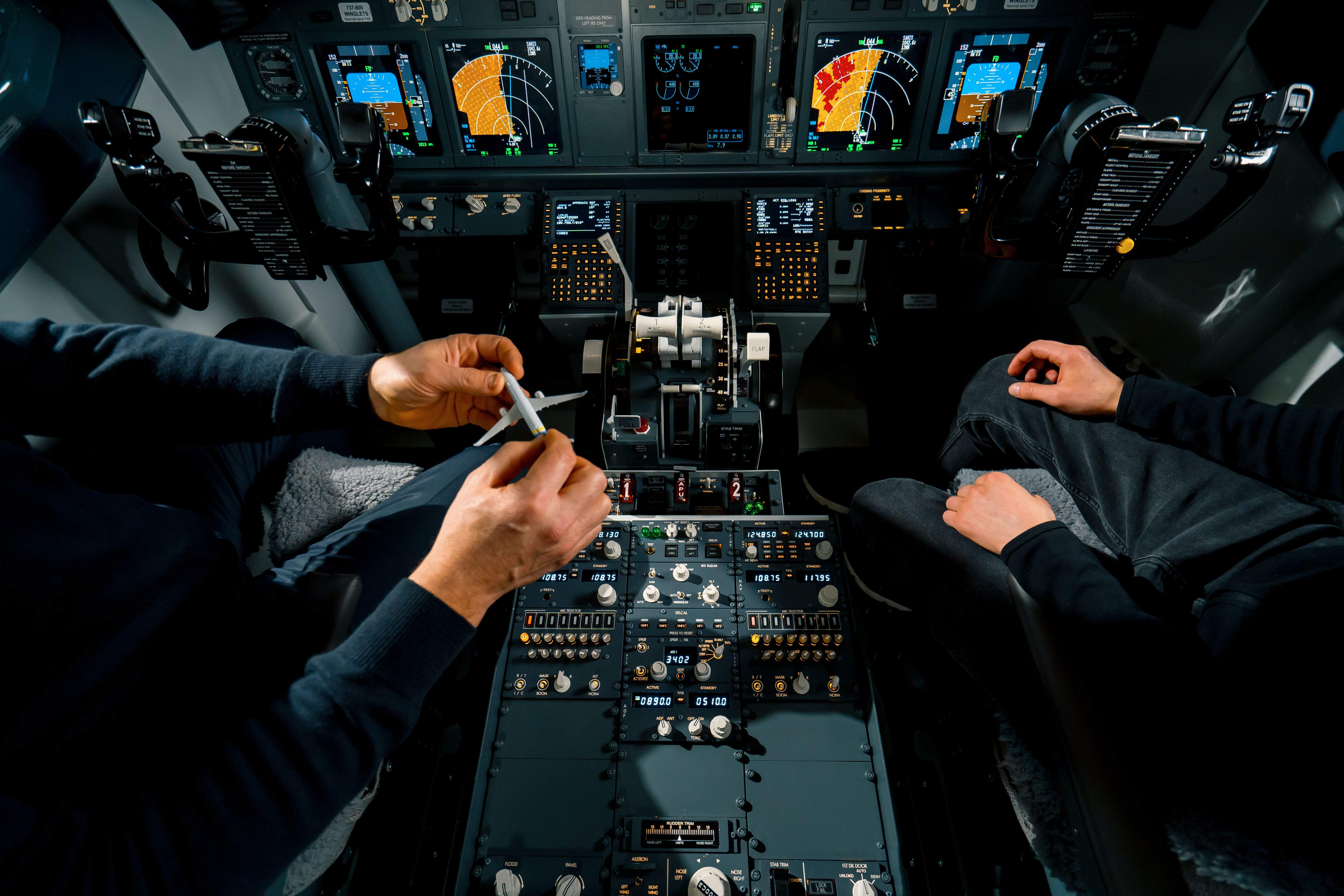 Pilots examining miniature aircraft model in simulator training