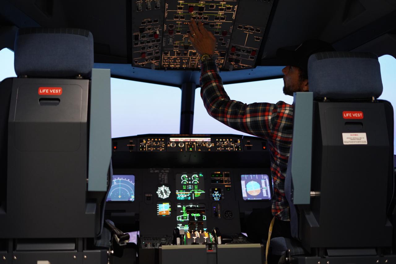 Flight simulator instructor operating overhead panel inside Boeing 737 MAX cockpit at WeFly Pasadena