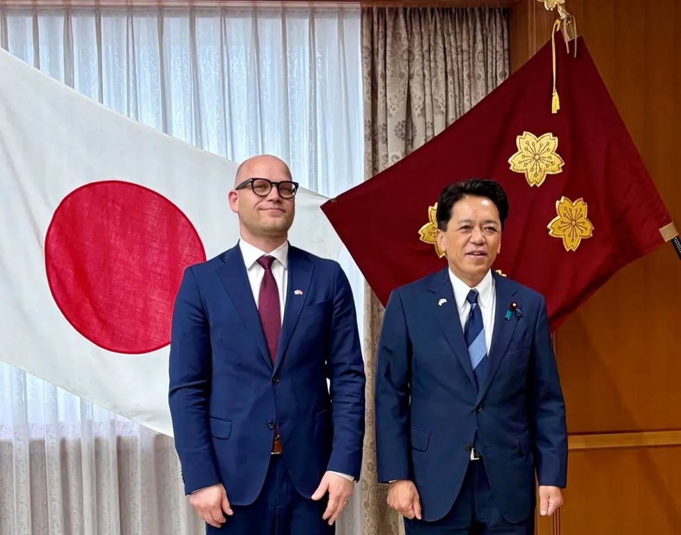 Statssekreterare Andreas Flåm och japansk viceminister skakar hand framför norska och japanska flaggor.