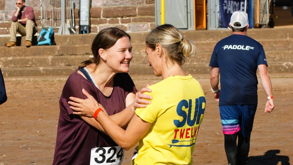 Competitors embrace on the beach