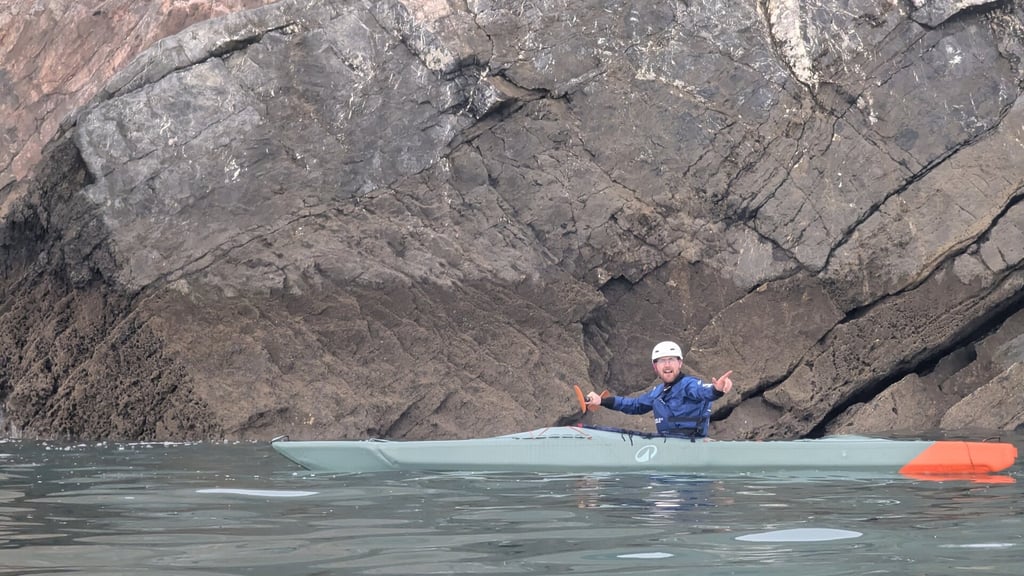Craig in a sea kayak by a rock formation