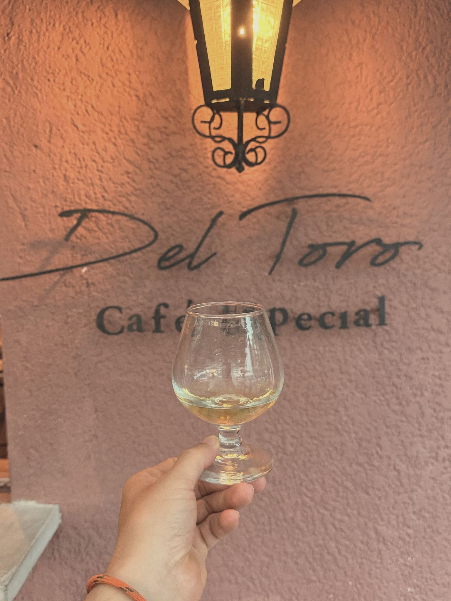 El letrero de Del Toro Café Especial en la fachada de noche, con el farol encendido y una copa levantada