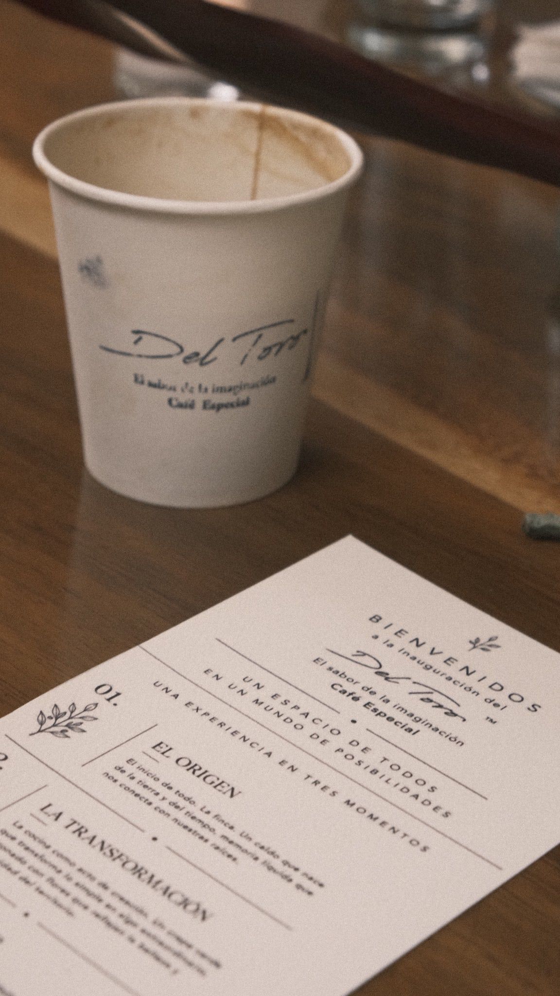 Un vaso de papel con la firma de Del Toro junto a la tarjeta de bienvenida de la inauguración